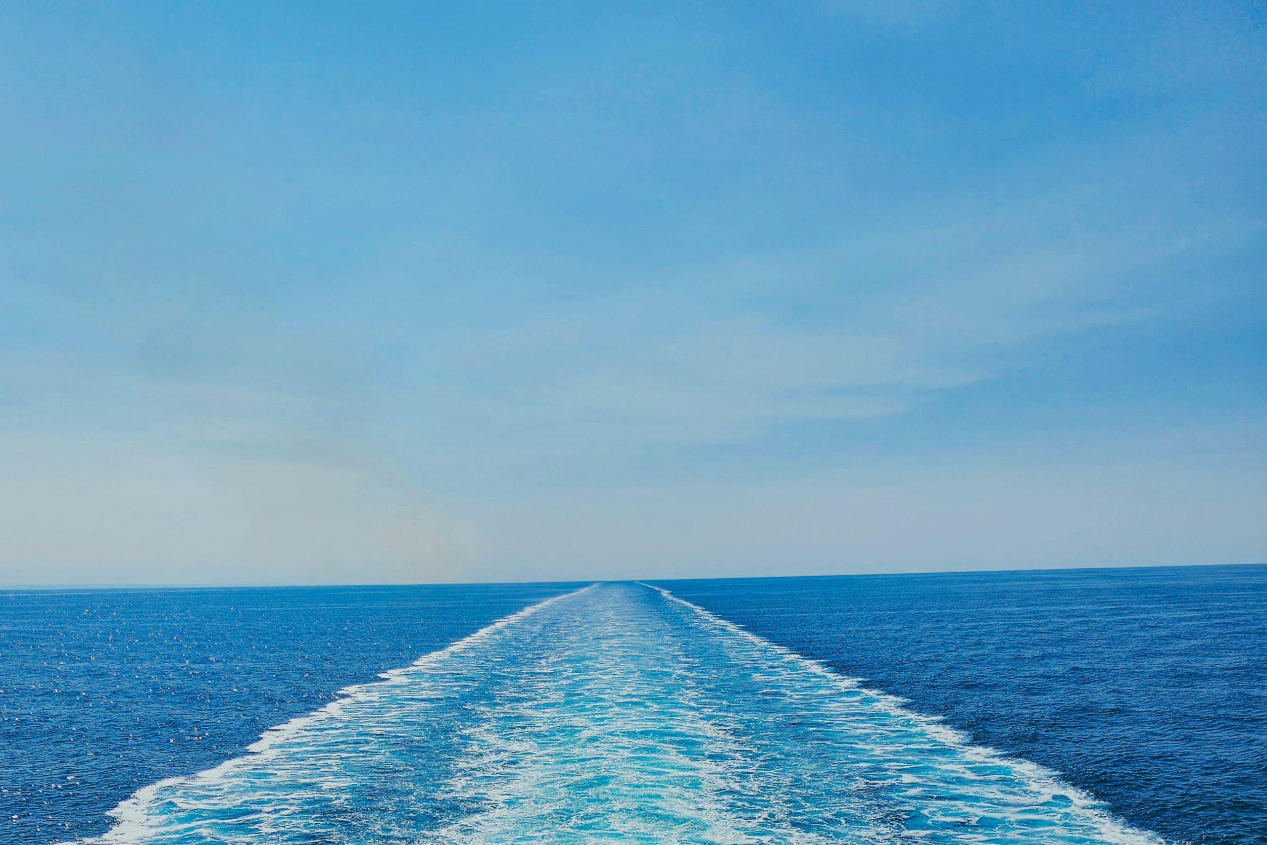 Open ocean horizon with a ship wake trail symbolizing global maritime provisioning, offshore logistics, and worldwide fleet support by IFS.