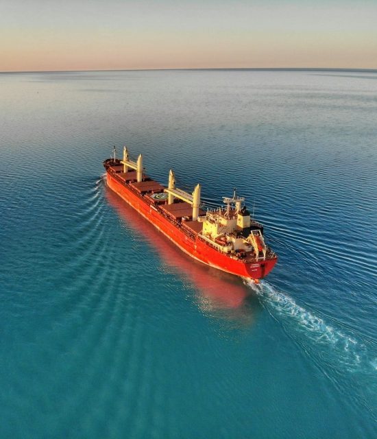 Merchant cargo vessel sailing across calm waters representing global maritime catering and logistics support services.
