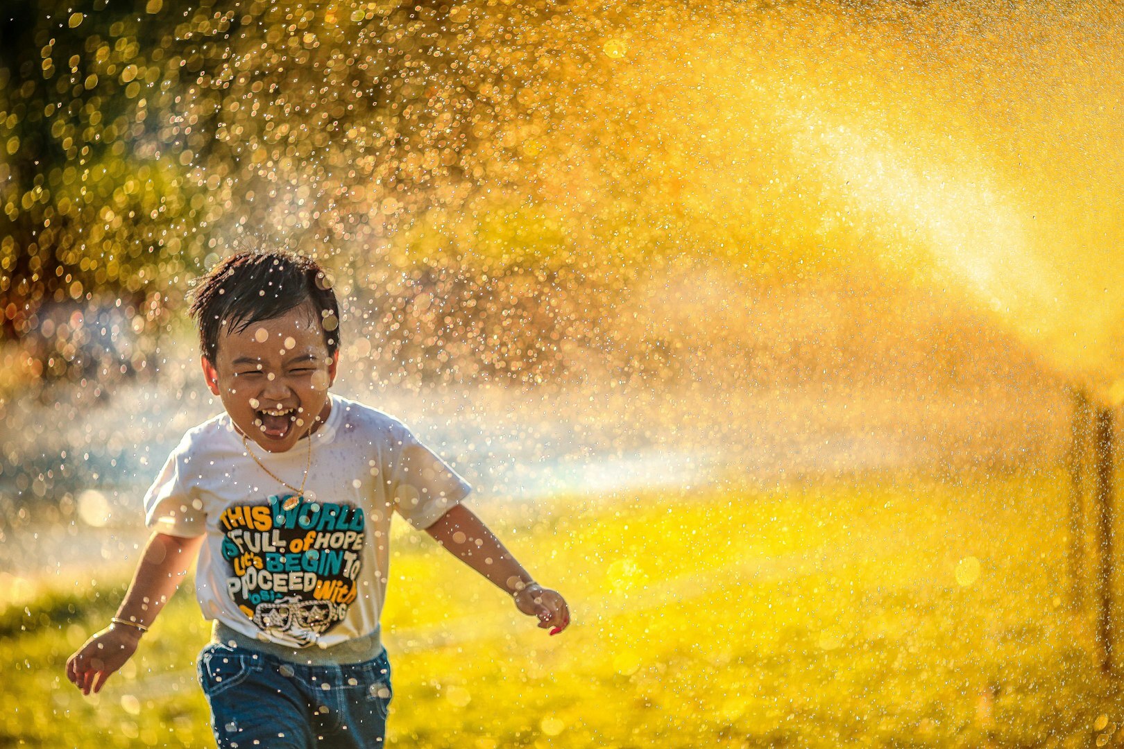 Children playing outdoors under water spray, representing community support, inclusion, and positive social impact initiatives by IFS.