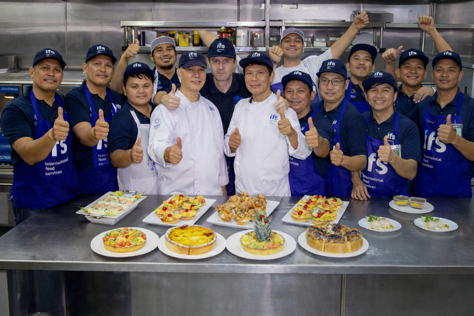 IFS catering and hospitality team onboard a vessel kitchen presenting prepared meals and showcasing maritime food service excellence.